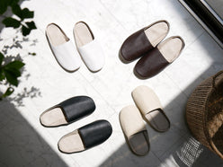 サラサデザインのプレーンステッチルームシューズ。白と黒の合成皮革を使用した快適な室内用スリッパ