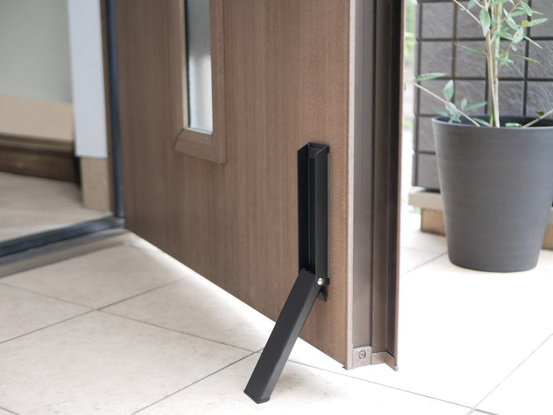 マグネット式折りたたみドアストッパーが木製フローリング上に設置されている様子