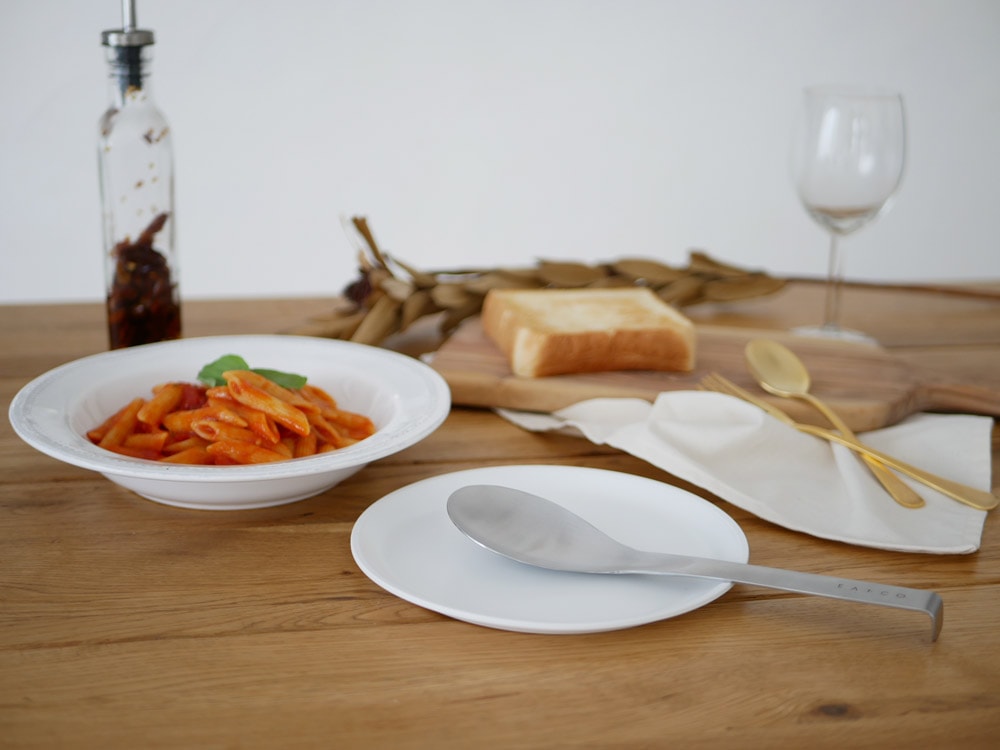 ステンレス製のスプーンとプレートが並ぶ食卓