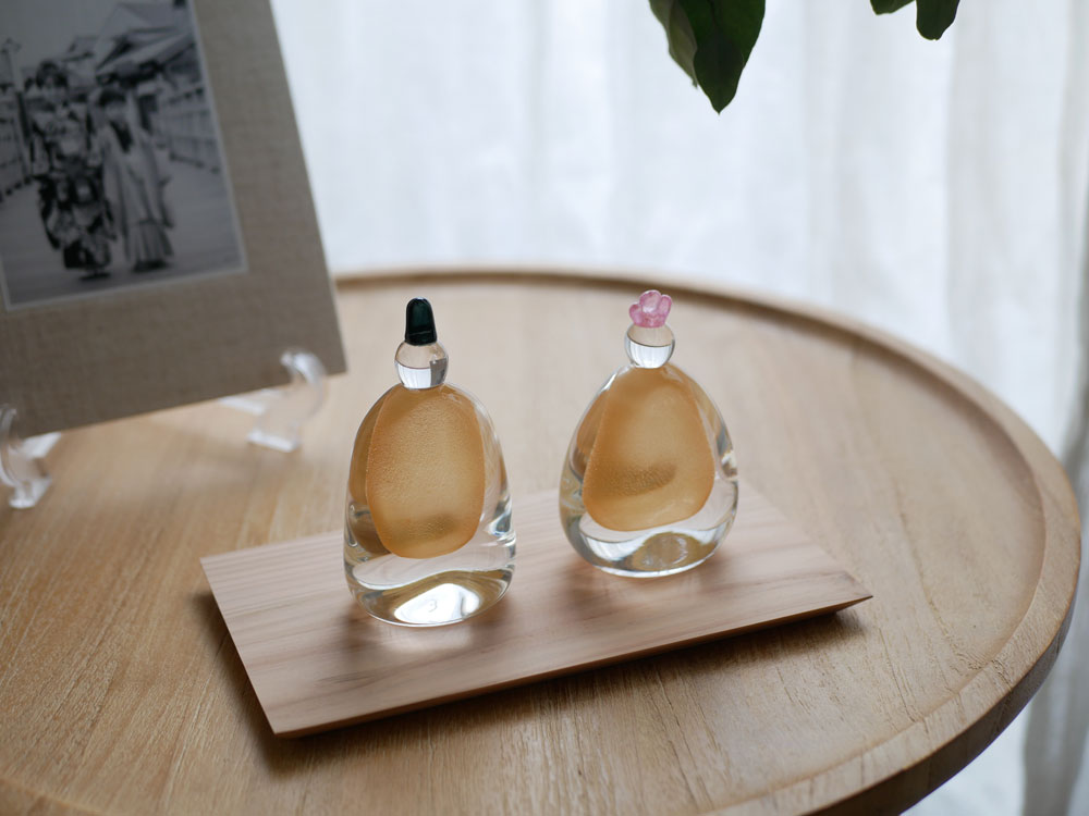 硝子屋 PRATO PINO製のガラスお雛様が木箱と飾り台に美しく飾られている静物写真