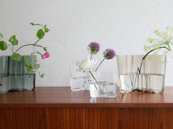 フィンランド製イッタラ アルヴァ・アアルトコレクションの透明な無鉛ガラスベースに、ガーメニウムを含むカットフラワーが美しくアレンジされた花束が飾られています。