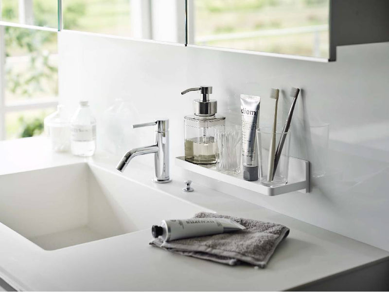 バスルームの洗面台に取り付けられた【MIST/ミスト】フィルムフック トレー W30。蛇口やキャビネット、石鹸ディスペンサー、ボトルが整然と配置されたカウンタートップ