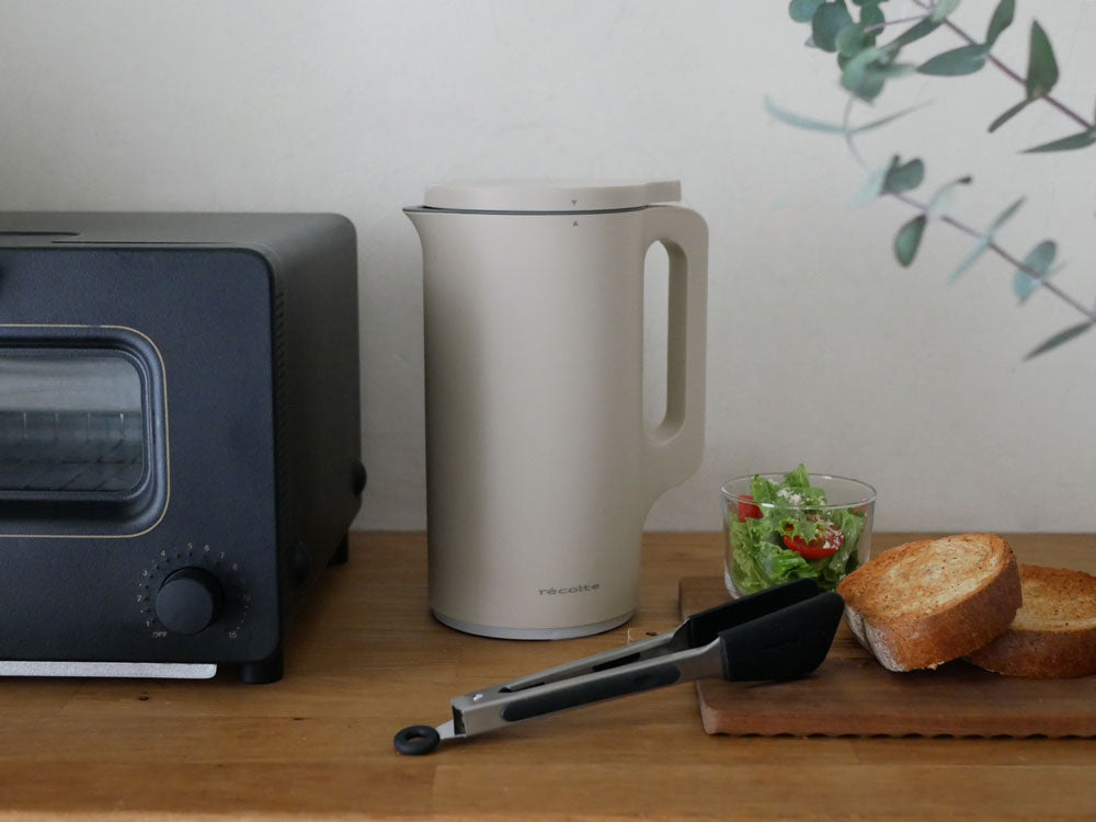 recolte自動調理ポット本体とフタ、計量スプーン、お手入れブラシが並んだキッチン家電の画像