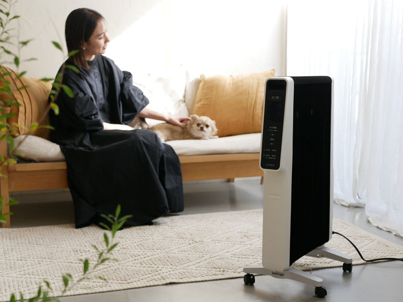 リビングルームの木製フロアに置かれたシロカ製遠赤軽量ヒーター「かるポカ」。周囲に家具が配置され、快適な空間を提供する様子。