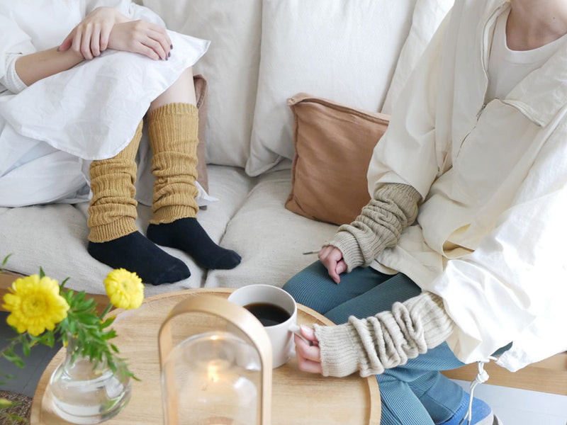 カシミヤコットンアーム&レッグウォーマーがクッションやソファとともに配置された快適なリビングルームの風景