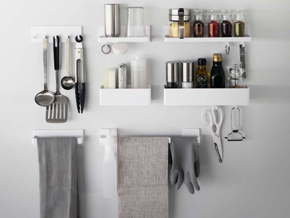 白色のフィルムフックトレーがキッチンの棚に設置され、食器や調理器具が整理されている様子