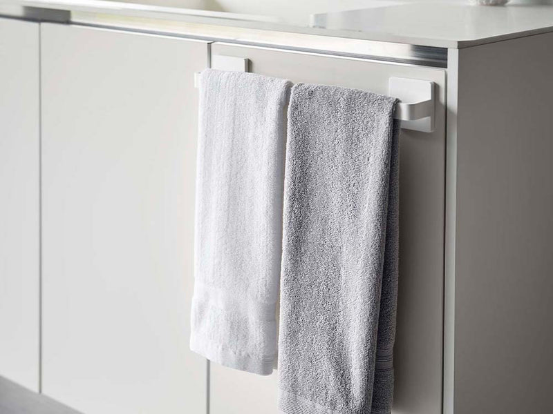 ホワイトのフィルムフック タオルハンガー W36が浴室の壁に取り付けられ、タオルを掛けている様子