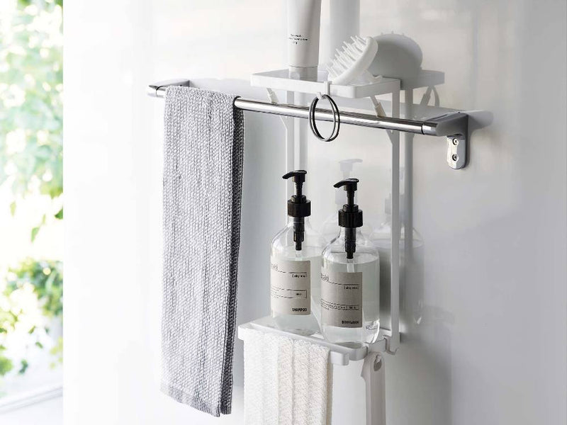 バスルームの壁に取り付けられたホワイトのタワータオル掛け上ラック2段で、タオルや歯ブラシホルダーが掛けられている様子