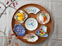 アマブロのMAMEシリーズから、吹墨富士形や吉祥魚形など多様なデザインの磁器皿が並ぶ食器セット