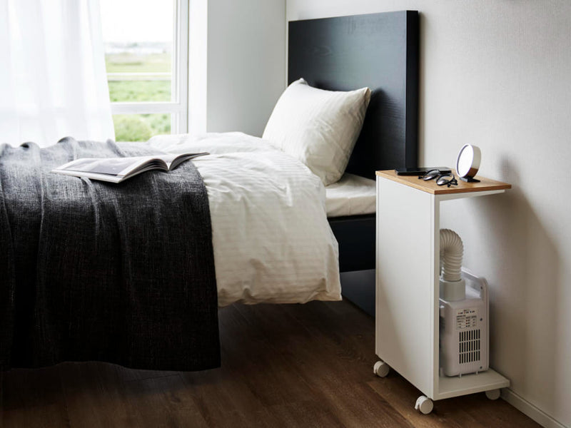 タワーキャスター付き目隠し布団乾燥機スタンドが木製フロアのベッドルームに配置されている様子