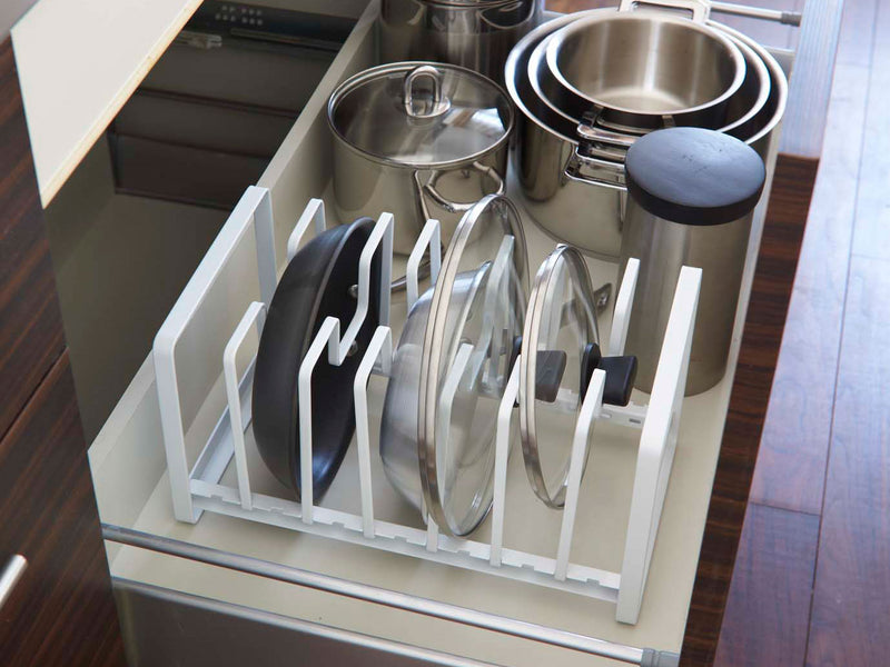 YAMAZAKI製タワー型フライパン&鍋蓋スタンドがキッチンキャビネット内に設置され、スチールとアルミニウム製の調理器具や食器が整然と並べられています。