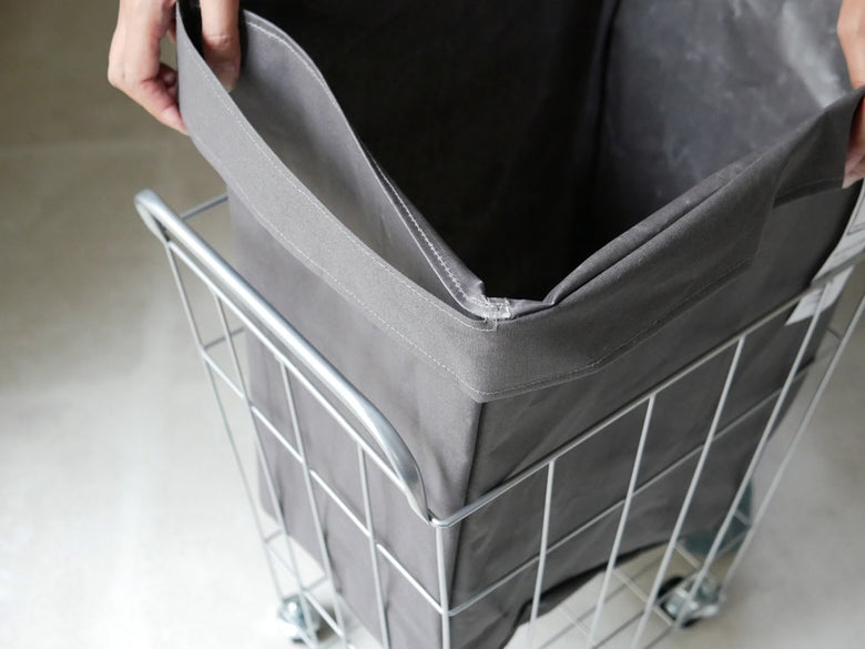 BRIDブリッドのランドリーストレージスクエア45L、銀色のハンドル付き灰色の収納バッグがキャスター付きカートに取り付けられている様子
