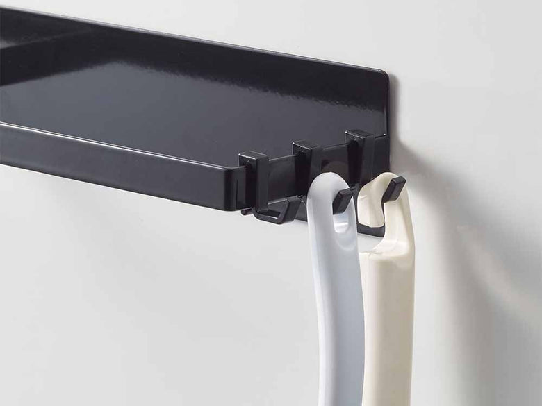YAMAZAKI/towerブランドのマグネット洗濯ハンガー収納ラック。スチール製の2段ブラケットが平らな壁面に取り付けられ、マグネットフックで衣類を掛けて収納しています。