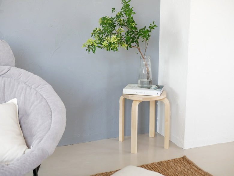 アルテックの灰色木製スツール60がリビングルームの木の床に配置されています。