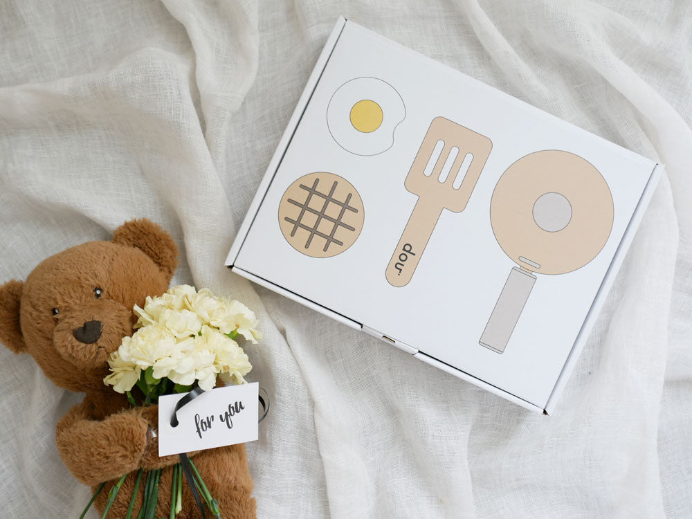 douブランドのままごとがっき pop pan キッチンセットとおもちゃのフライパン、スプーン、食器、フィンガーフードが並んでいる様子