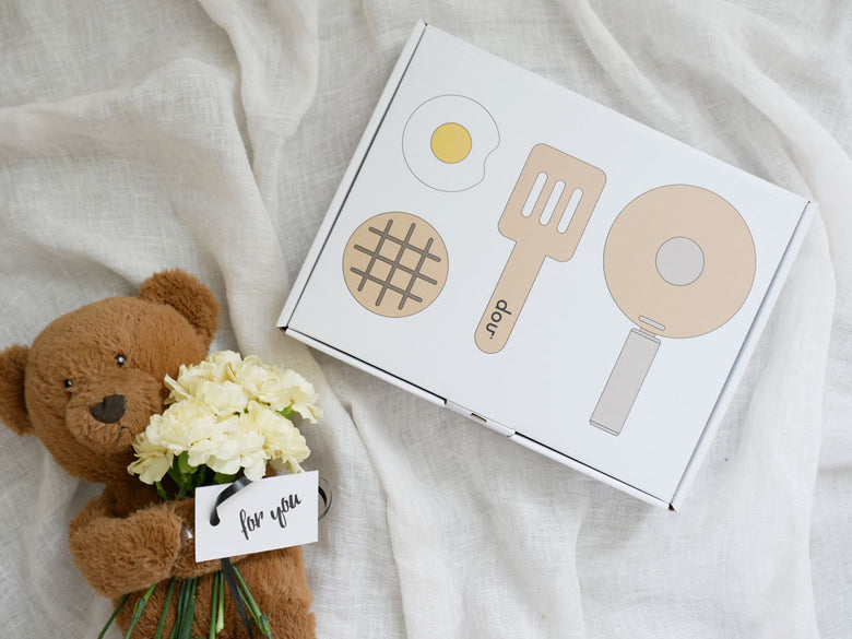 douブランドのままごとがっき pop pan キッチンセットとおもちゃのフライパン、スプーン、食器、フィンガーフードが並んでいる様子