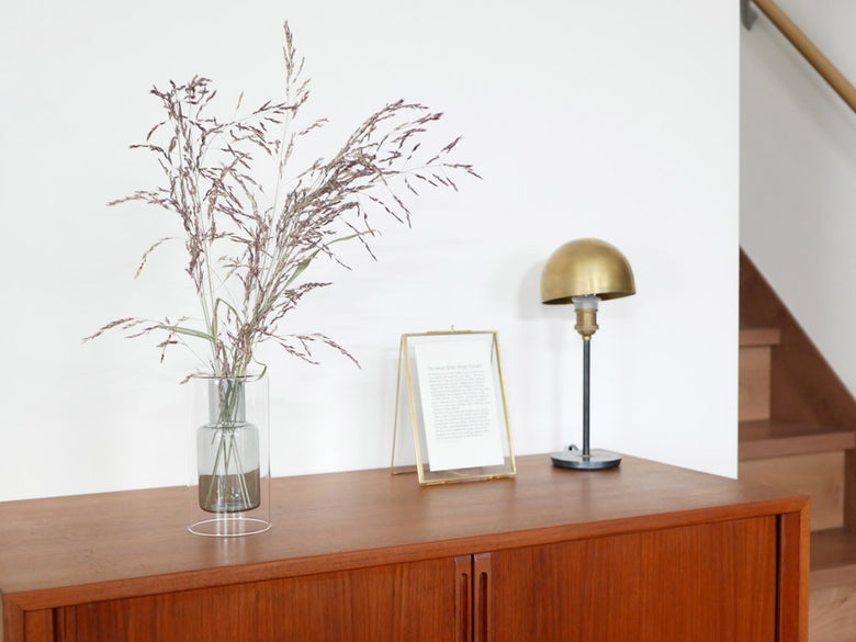 木製家具の上に置かれたPOSH LIVINGのガラス製フロートベースと花。リビングルームのインテリアデザイン。