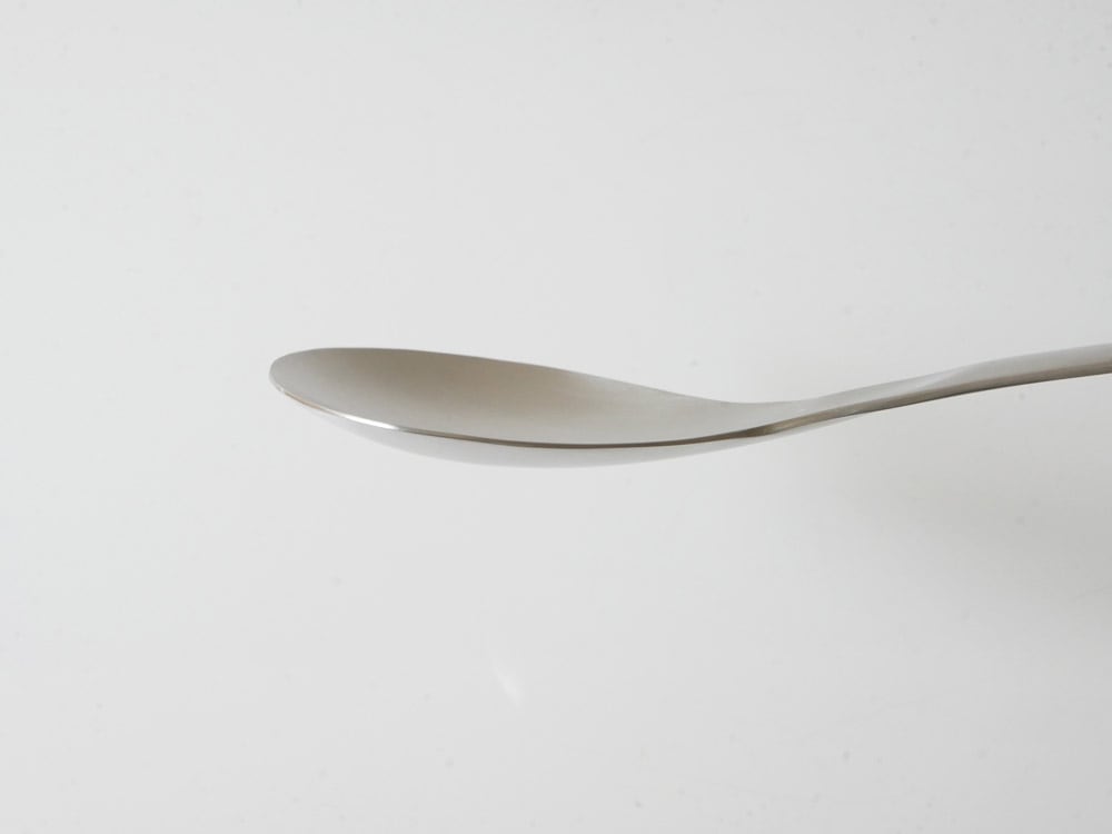 ステンレス製のスプーンと食器の静物写真