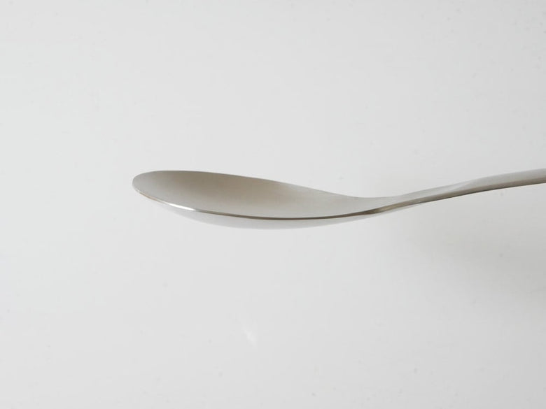 ステンレス製のスプーンと食器の静物写真