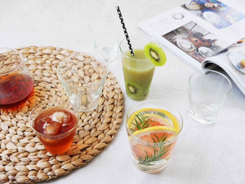 Horn Pleaseのティーグラスがテーブル上に配置され、果物とノンアルコールドリンクと共にスタイリッシュに展示されています