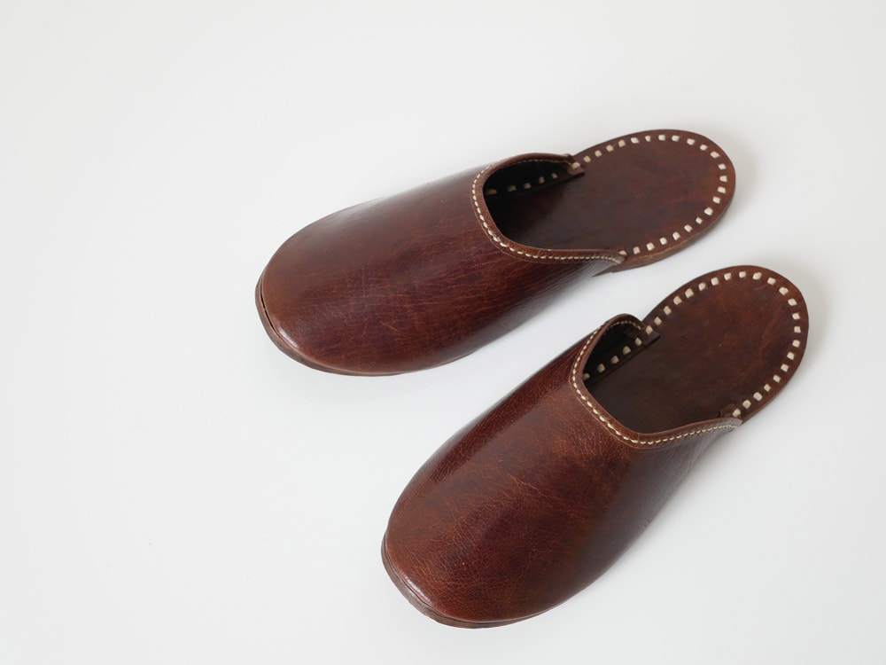 ブラウンの水牛革スリッパ。リネンステッチが施されたストラップ付きスライドサンダル