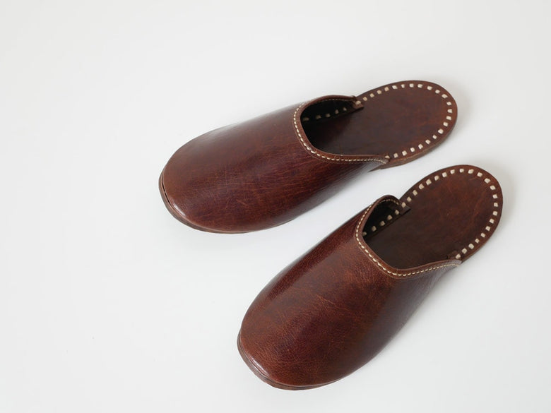ブラウンの水牛革スリッパ。リネンステッチが施されたストラップ付きスライドサンダル