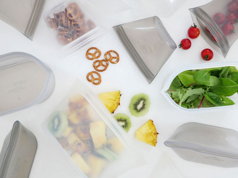 Zip Topブランドのプラチナシリコーン製食品保存容器セット。異なるサイズの容器に果物や野菜が入っており、蓋付きトレイが重ねられたキッチン用品の写真