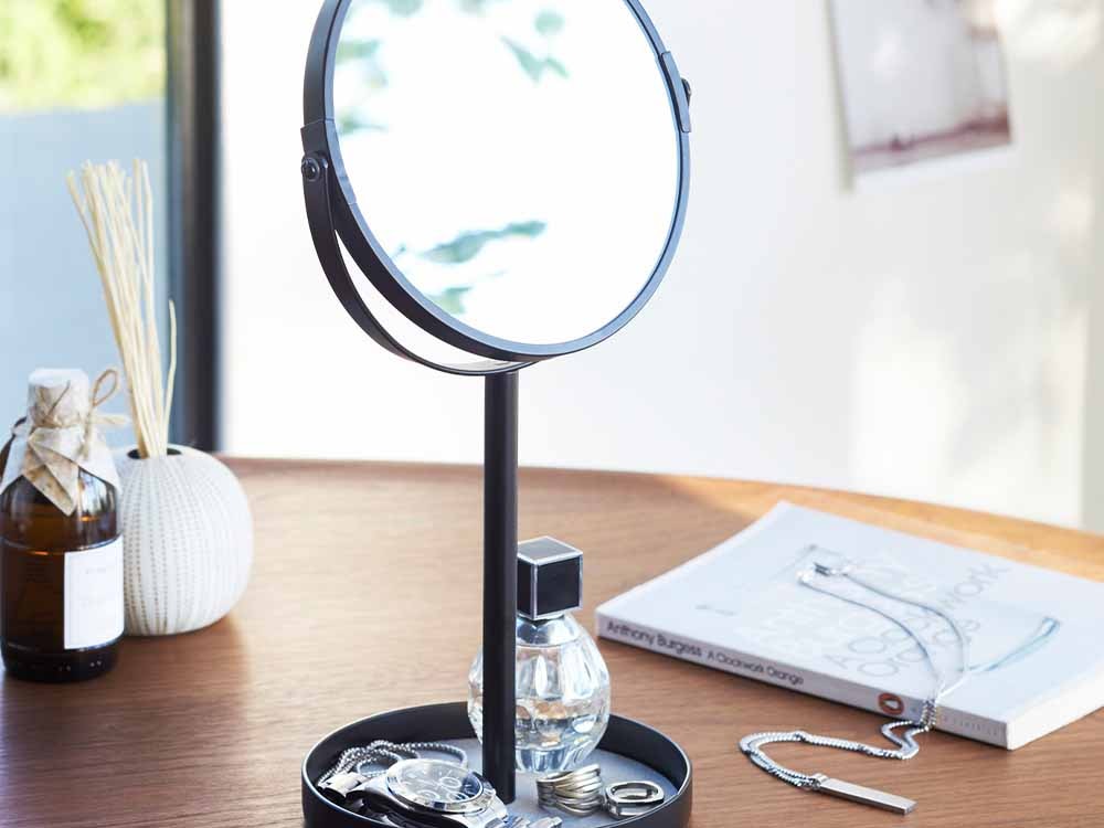 Yamazakiタワーのスチール製スタンドミラー&トレイがデスク上に設置されており、フェルトマット付きの2mm厚ガラスミラーと実用的なトレイが一体化したオフィス用品。