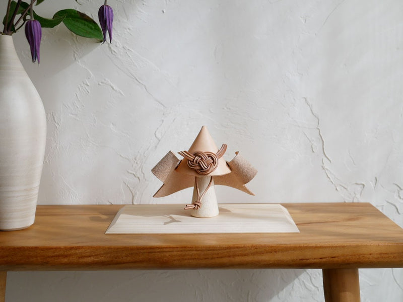 Comore Sunブランドのヌメ革製こども用兜。ブナのスタンドとヒノキの台座がセットになった天然素材のクラフトアイテム