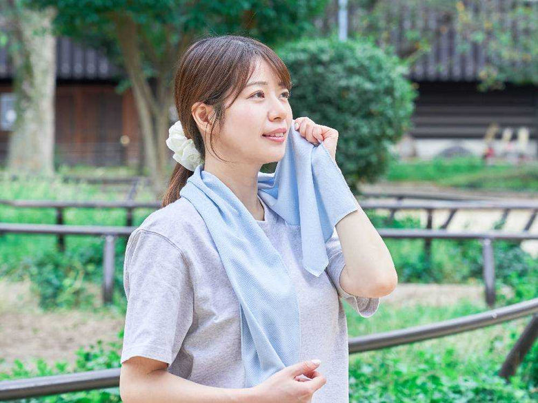 笑顔のモデルがヒヤシーナ氷タオルを持つ