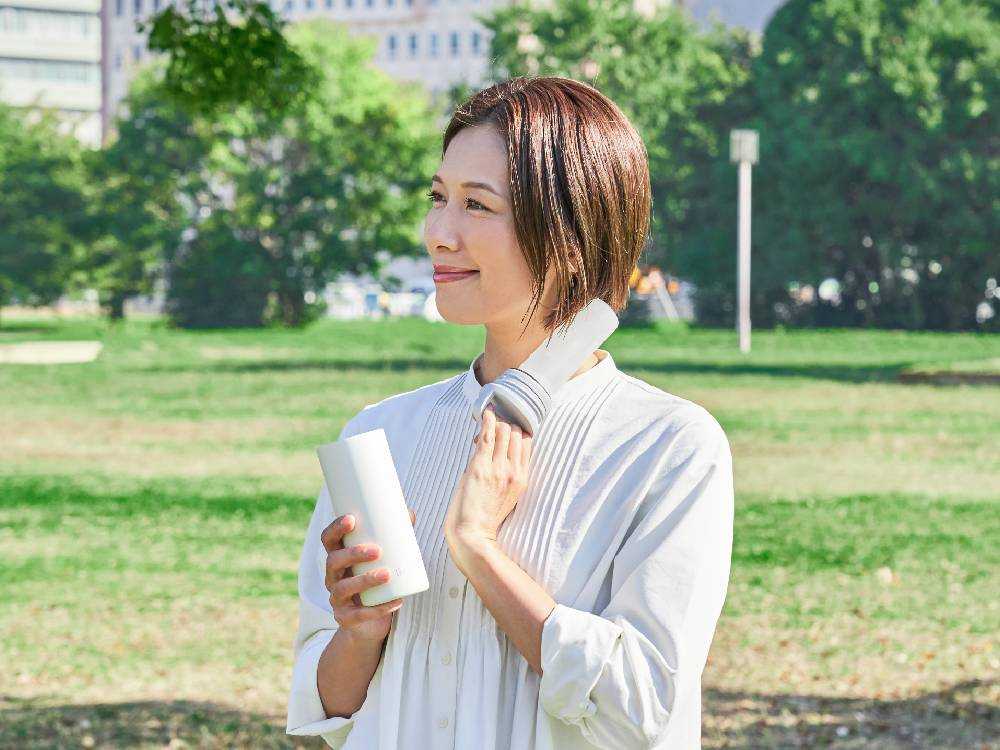 笑顔の女性がスマホを操作しながら冷感マフラータオルを使用