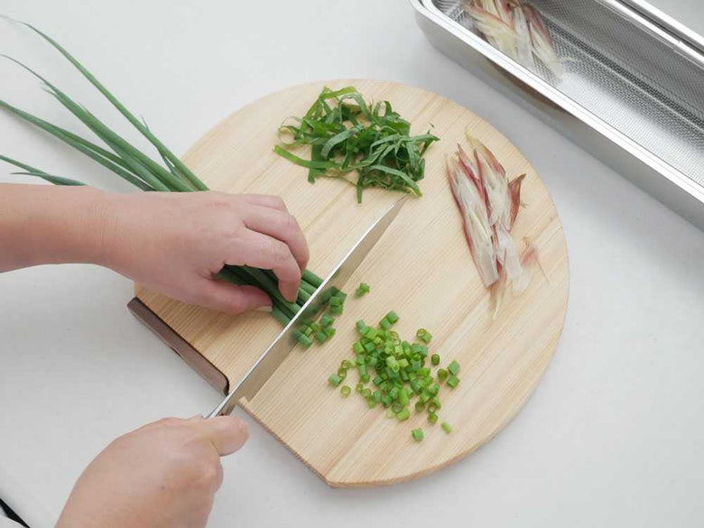 ヒノキ製まな板と野菜、調理器具が並ぶキッチンカウンター