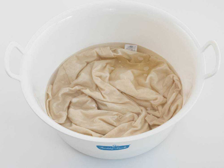 オキシクリーンのプラスチック容器と蓋が木の床に置かれた写真