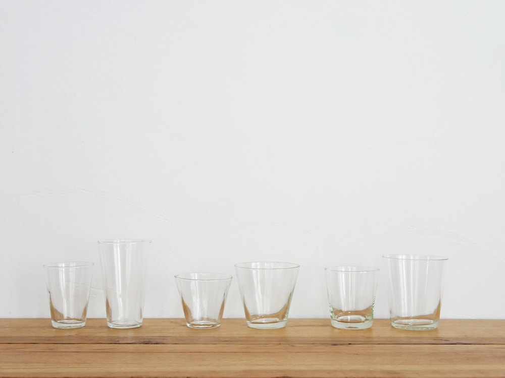 ホーンプリーズのリサイクルガラス製グラスセット。オールドファッションドグラスやハイボールグラス、ショットグラス、パイントグラスなど多様な形状の手作りグラスが並んでいる。