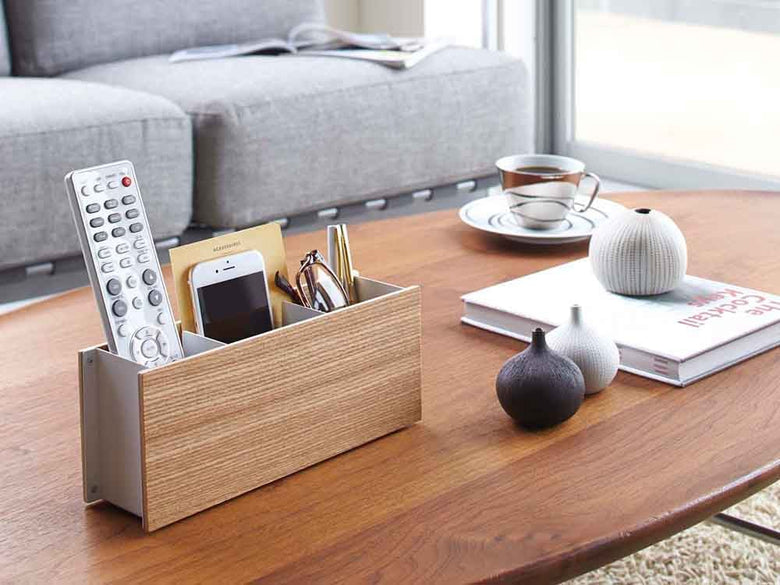 オフィスデスクに置かれたYAMAZAKI/RIN製のスチールと木材のペン＆リモコンラック。ペンやリモコンが整理されています。