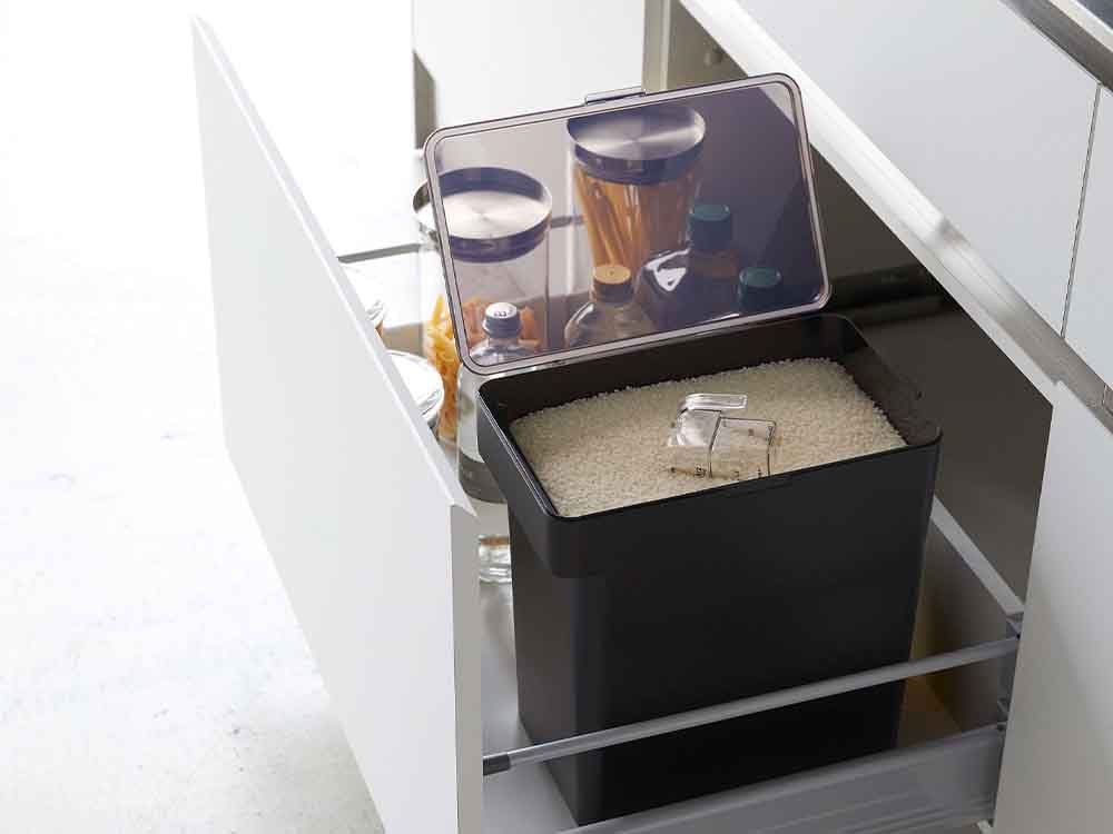 灰色のキッチン棚に置かれたタワーの密閉米びつと計量カップ