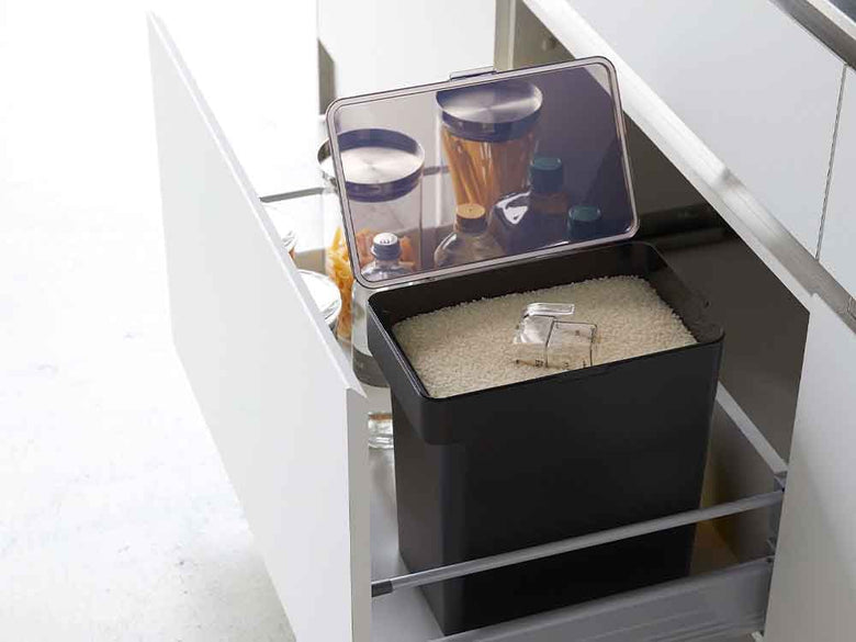 灰色のキッチン棚に置かれたタワーの密閉米びつと計量カップ