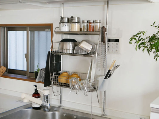 bws SELECTIONの流れるつっぱり水切りラックがキッチンの棚に取り付けられ、食器や調理器具を整然と収納・乾燥させている様子