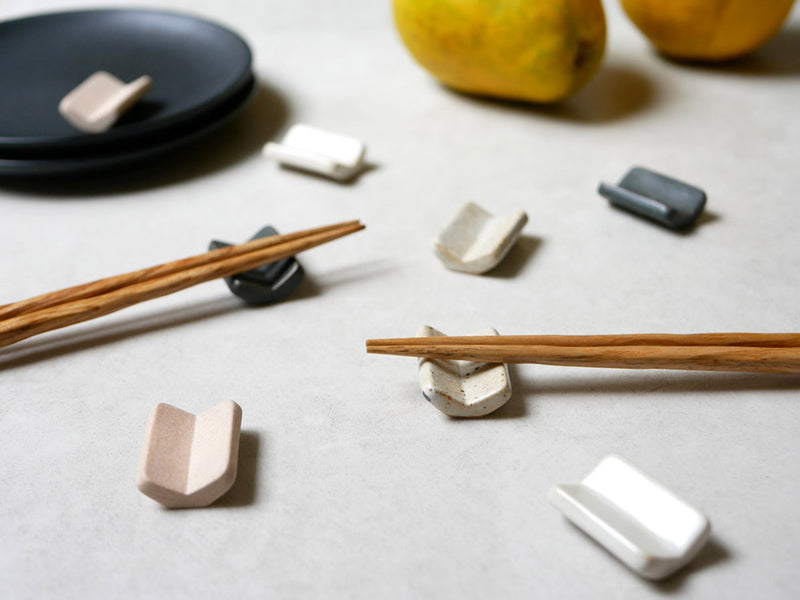 白い陶器製の箸置きが木製テーブル上に配置された静物写真