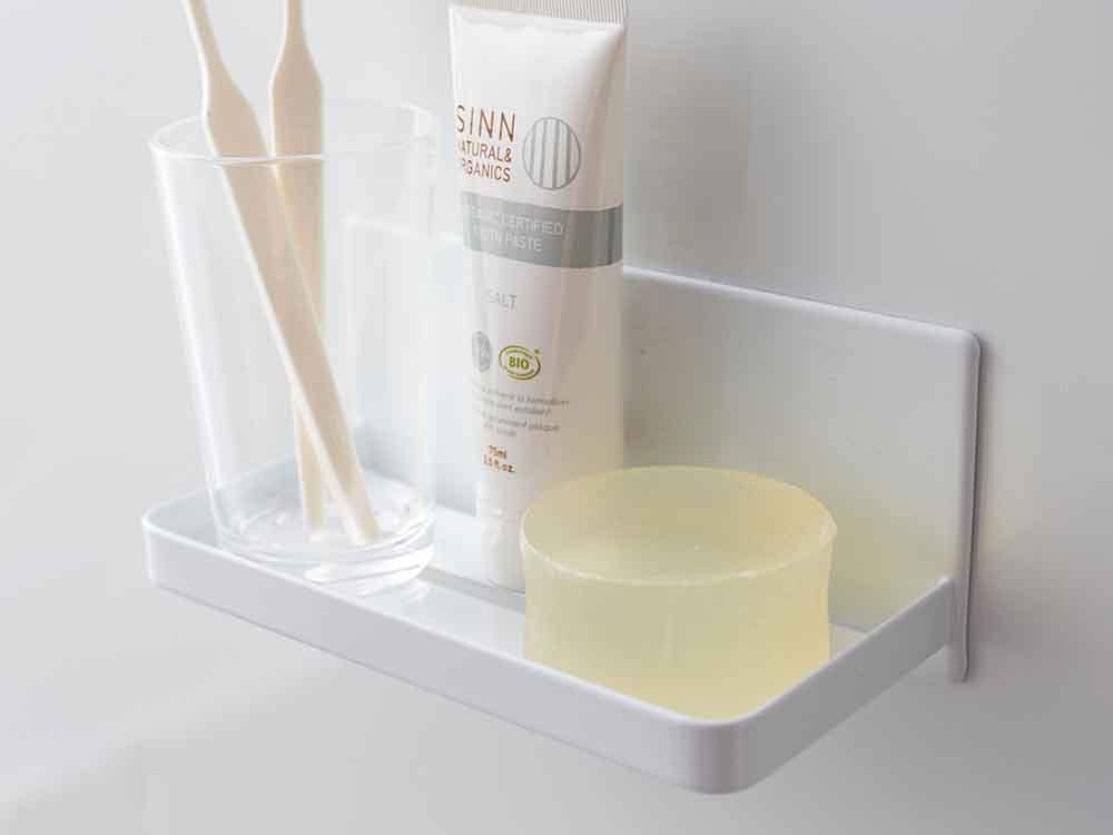 YAMAZAKI/towerのマグネットバスルームラックが浴室のスチール棚に設置され、プラスチック製ボトルやソープディスペンサーが整然と並んでいる様子