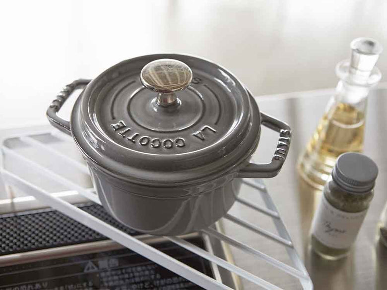 YAMAZAKI/towerブランドのコンロコーナーラックに、シルバーの調理器具や食品保存容器が整然と配置されている様子