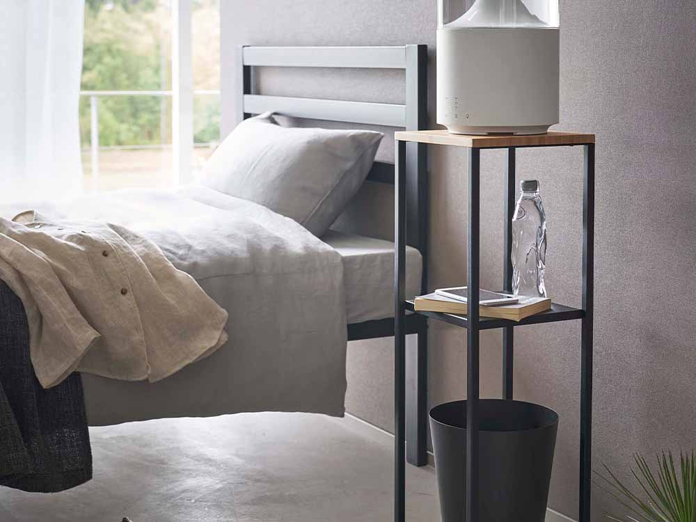 グレーのtower加湿器スタンドがベッドサイドに設置された寝室