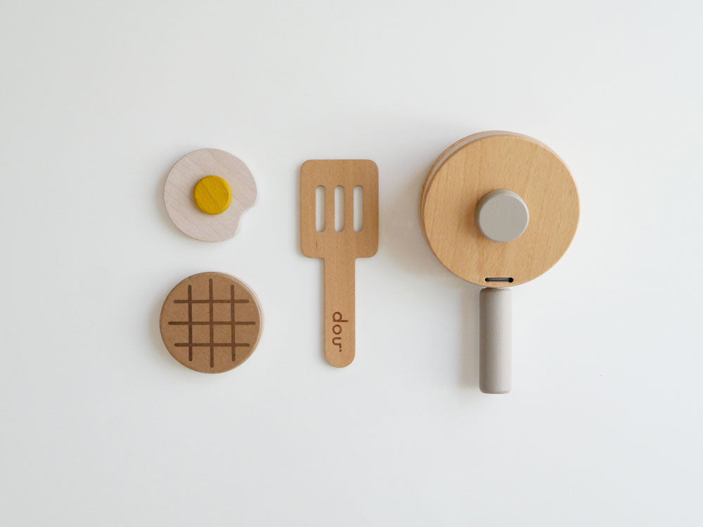 ままごとキッチンセット「pop pan」のピザカッター、ヘラ、スプーンなどのキッチン用具が切り板の上に並んでいる