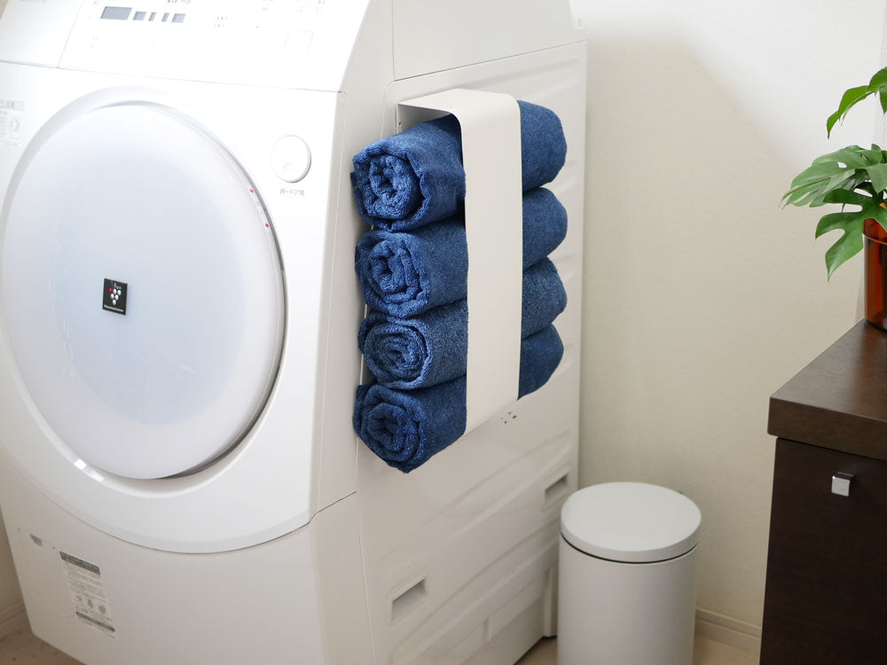 YAMAZAKI製スチールマグネットバスタオルホルダーが洗濯機と乾燥機の近くに設置され、約4枚のバスタオルを掛けている様子