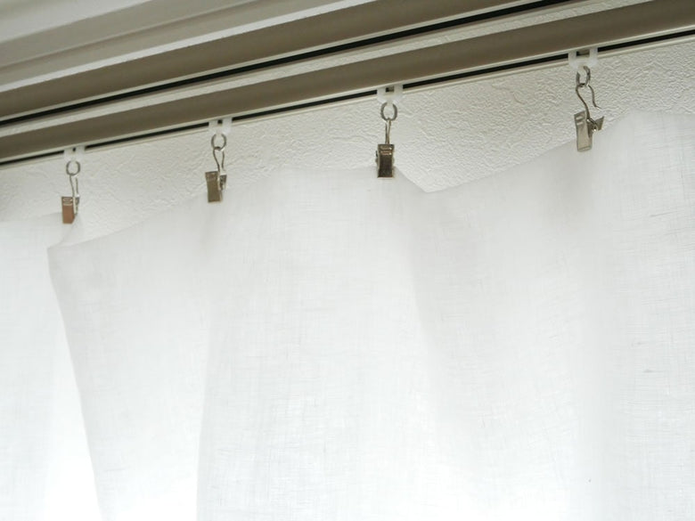 銀色のカーテンクリップが掛かったシャワーカーテン