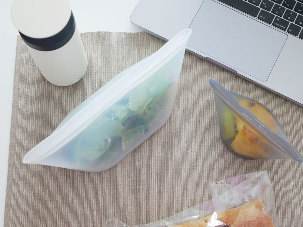 Zip Topブランドのプラチナシリコーン製ディッシュが果物や食品とともにキッチン用具やトレー上に配置されている様子