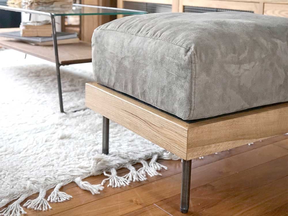 アデペシュのグレーオットマンが置かれた寝室のインテリア