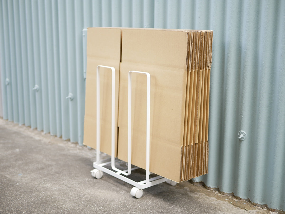 木製の床に置かれたYAMAZAKIのタワーダンボールストッカーと折りたたみテーブルおよび椅子の配置