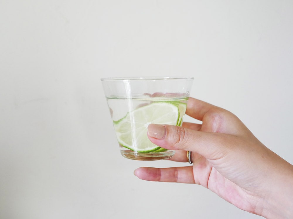 Horn Please（ホーンプリーズ）製リサイクルガラスのティーグラスにティーパンチとライムが入ったカクテル。手作りの高ボールグラスで、エレガントな飲み物を提供しています。