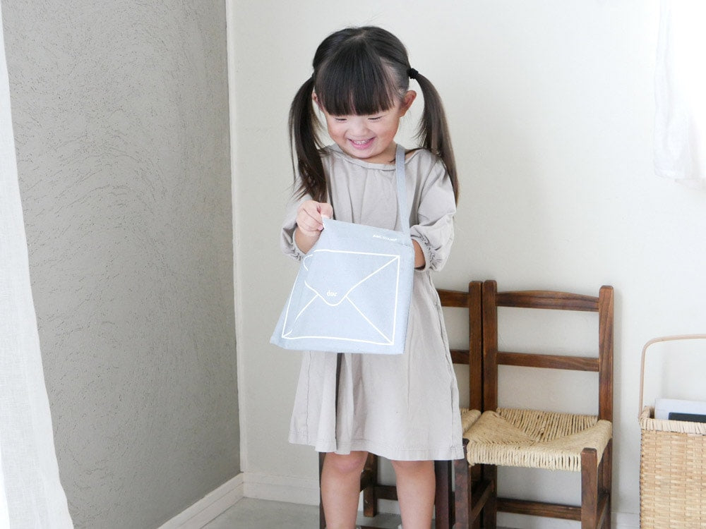 柄のワンピースドレスを着た子供がショルダーバッグを持つ姿